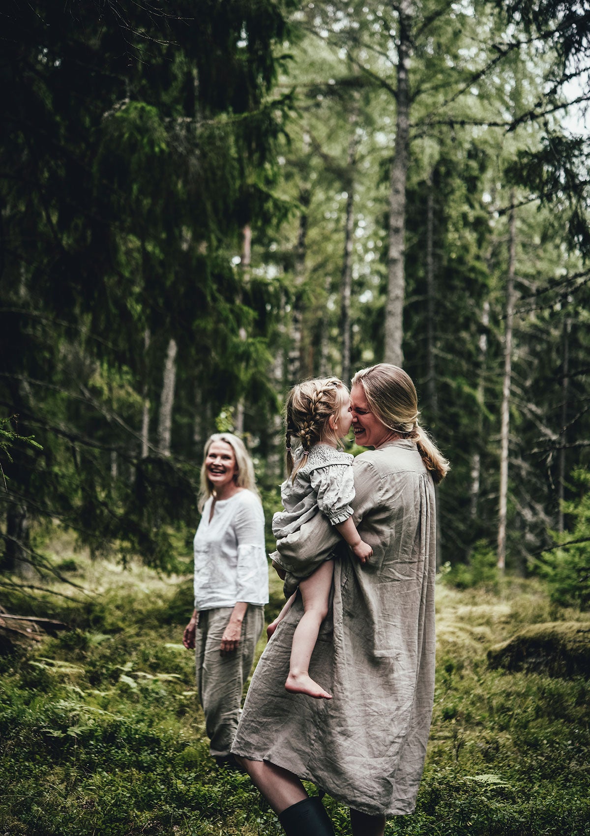 Niki Newd co-founder Kirsi Kaukonen picking wild blueberries in a Finnish forest with three generations of her family, embodying the brand's nature-rooted fresh cosmetics philosophy.