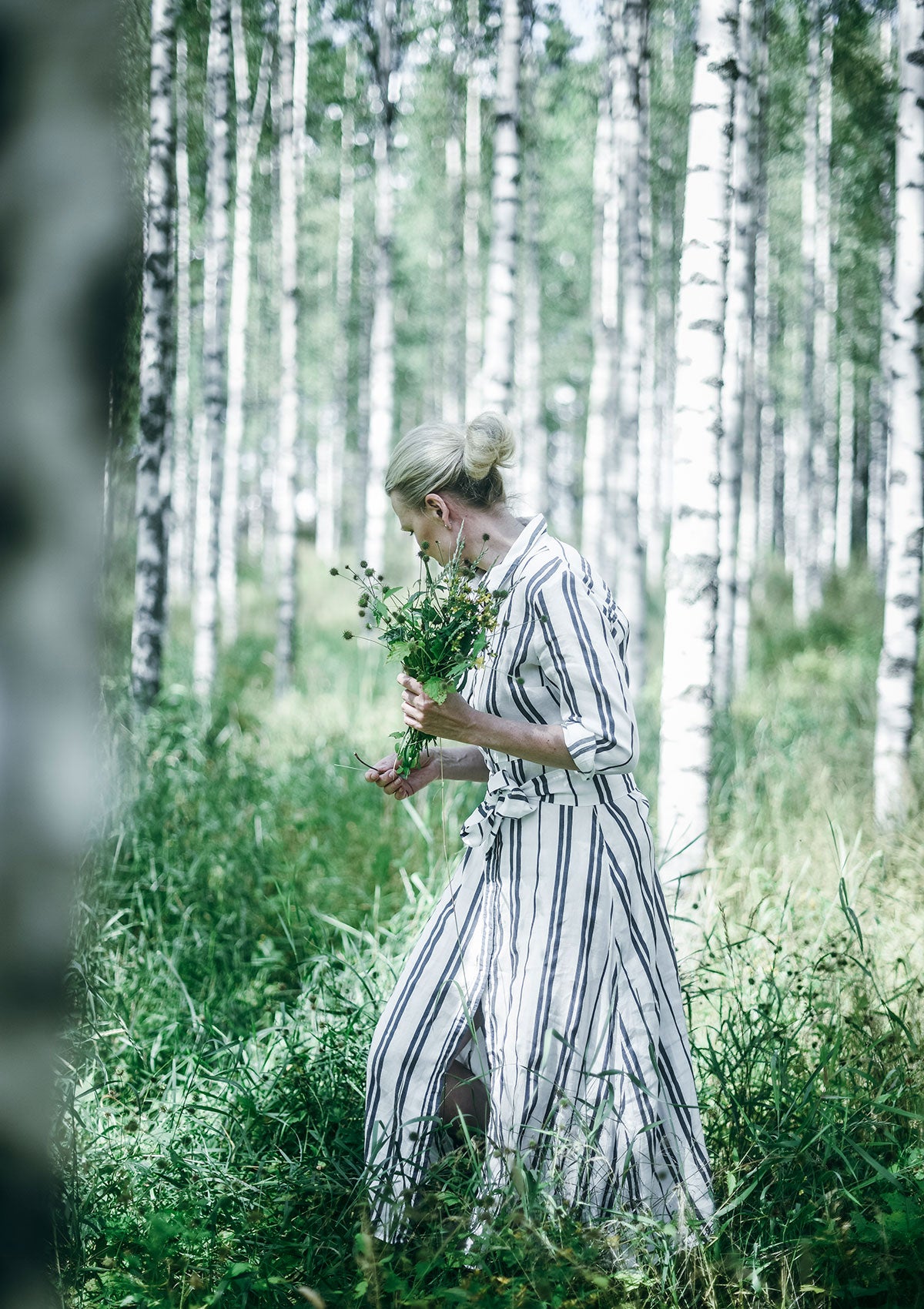 Niki Newd co-founder Kirsi Kaukonen gathering wildflowers at her Finnish summer cottage, the birthplace of the brand's nature-rooted skincare philosophy.