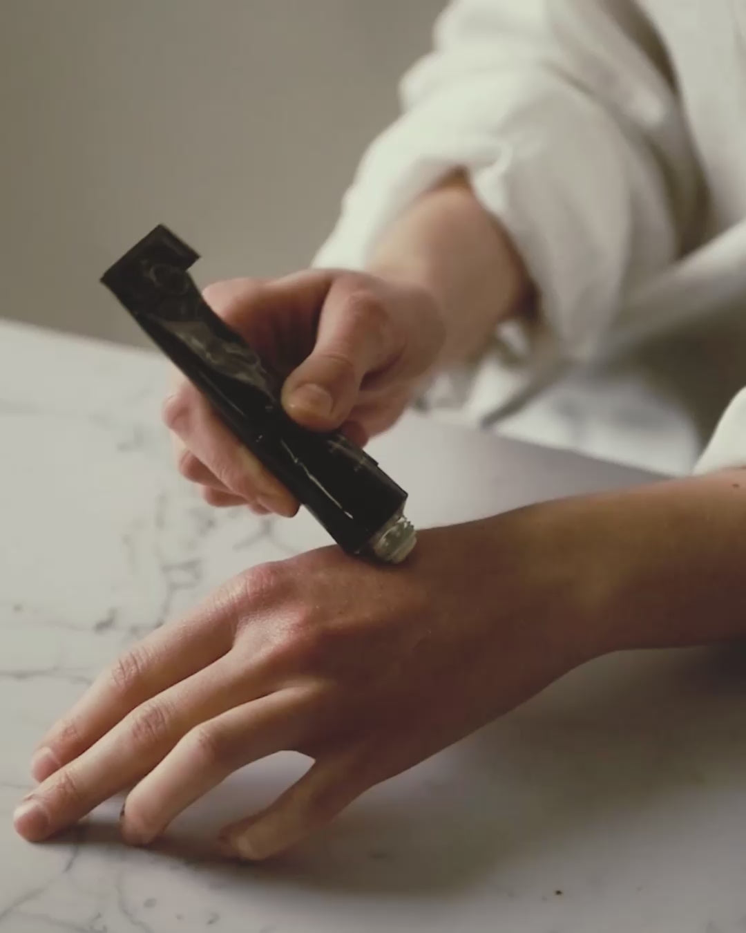 Close-up video showing the rich, dense texture of Niki Newd cream settling into a soft, luminous finish on the skin.