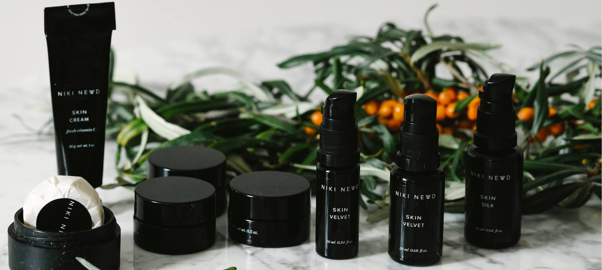 Niki Newd skincare products on marble background – Take the product recommendation quiz.